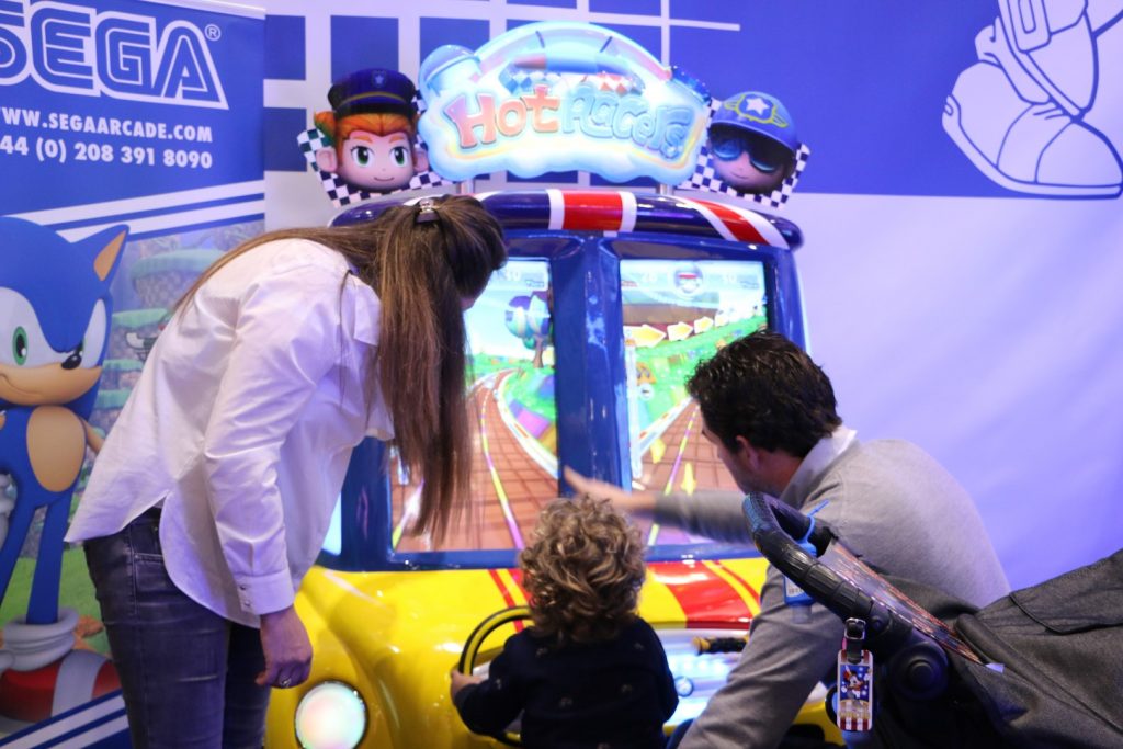 a family of three playing on the Hot Racers arcade amusement two-player driving machine